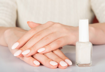 Obraz na płótnie Canvas woman's hands with white nail varnish bottles