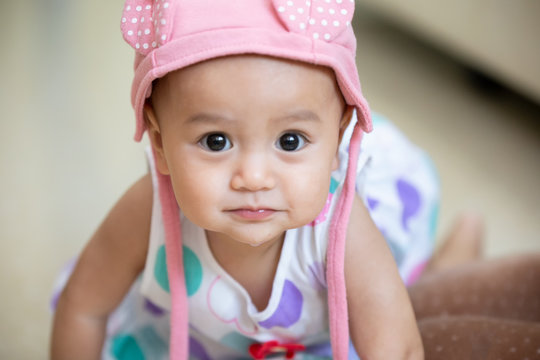 Image of sweet baby girl in a wreath, closeup portrait of cute 5 month-old smiling girl, with pink hat.
