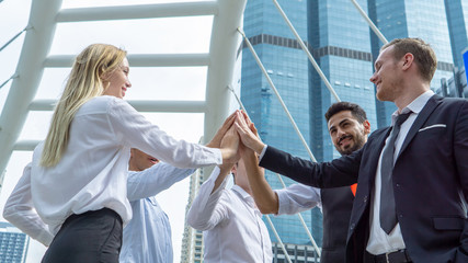 Closeup on hands. Colleague putting their hands on top of each other symbolizing unity and teamwork while doing activity outdoor. People joining hand together as a business goal achievement.