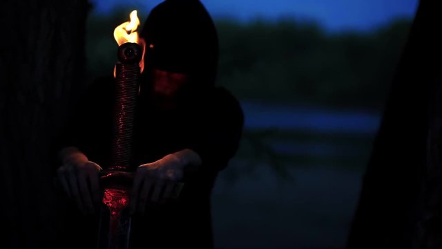 mysterious witcher in a cloak holding a fire man in fantasy medieval dress. Halloween