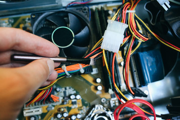 Inside details of the old personal computer. Motherboard and video card in the dust. Man is cleaning wires with a brush. Broken PC.