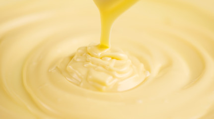 White chocolate. Pouring melted liquid white chocolate. Closeup of molten liquid hot chocolate swirl. Confectionery