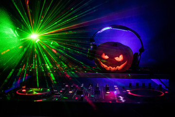 Halloween pumpkin on a dj table with headphones on dark background with copy space. Happy Halloween...