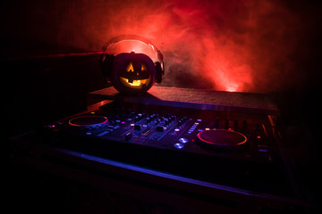 Halloween pumpkin on a dj table with headphones on dark background with copy space. Happy Halloween...