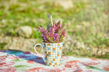A small bouquet of wildflowers is on the table in the cup