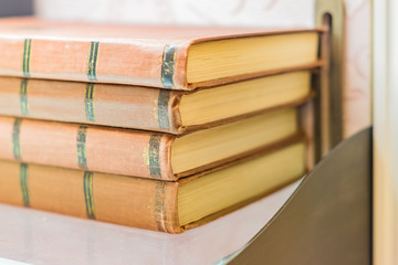 pile of old books with brown retro cover on shelf. Selective focus