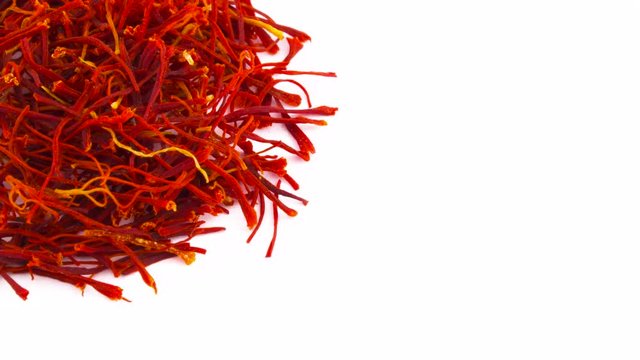 Half frame of one circle shaped saffron threads pile. Slowly rotating on the turntable isolated on the white background. Close up. Macro. Copy space.