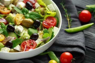 Healthy low calories salad with lettuce, heirloom tomatoes, avocado, feta cheese, red onion, cucumber, sweet peas, olives, thyme, mint and basil.