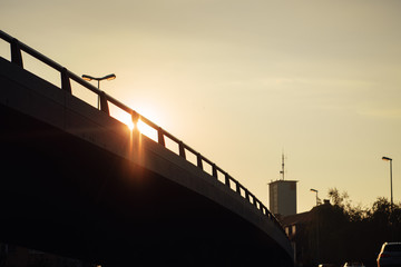 Urban bridge at sunset light and lens flare with a tower building in the background