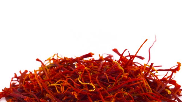 Macro shooting of upper part of red saffron threads heap. Slowly rotating on the turntable isolated on the white background. Close up.