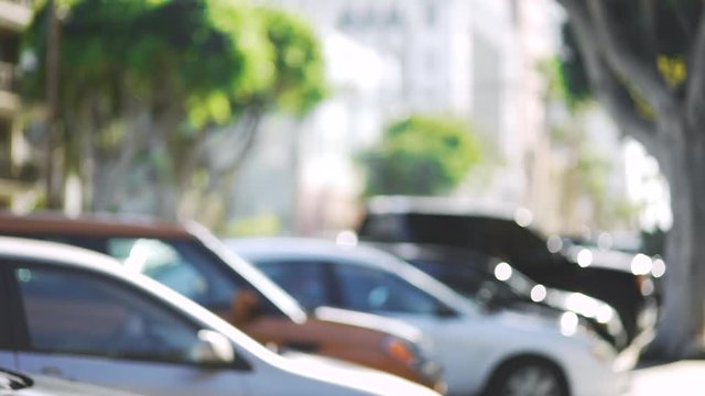 Out of focus video backdrop of parked cars on a downtown street with buildings