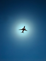 Airplane on a blue sky with sun in the background