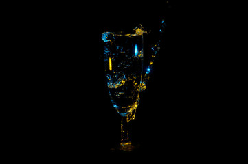 Beautiful yellow and blue bubbles in a fancy glass being filled with a beverage isolated on a black...