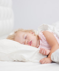 Obraz na płótnie Canvas little baby girl sleeping on a bed. Space for text