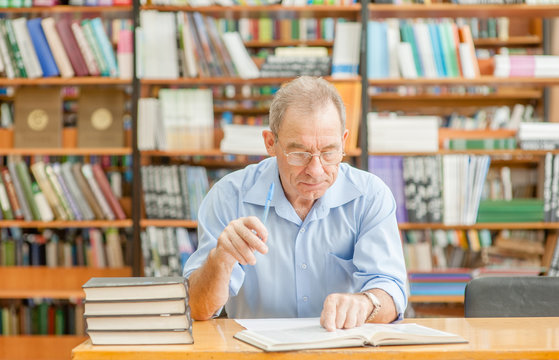 senior man reading a book in the library
