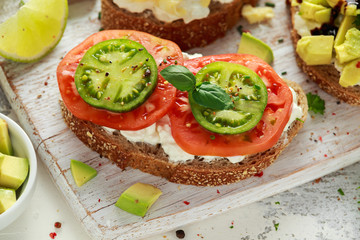 Vegetarian Healthy bread toasts with cottage cheese, heirloom tomatoes, scrambled eggs and avocado