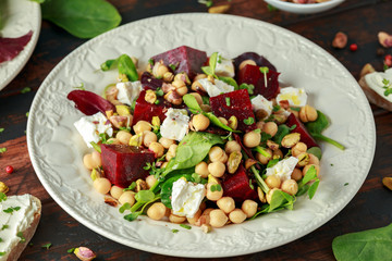 Healthy Beet Salad with chickpeas, pistachios nuts, feta and melted cheese toast on rustic wooden background