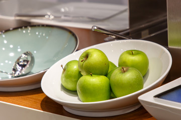 Green apples lie on a white plate.