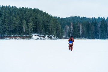 Fisherman is walking on a lake at winter