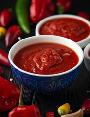 spicy hot sweet chili sauce with mix of chilli pepper, garlic and tomatoes on rustic wooden background