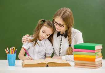 Teacher hugs a little sad girl at school