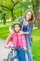 Happy young mother dresses her daughter's helmet