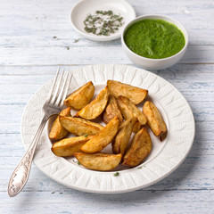 Baked potatoes with kale pesto sauce on a light blue background, selective focus. Delicious vegan homemade food