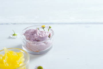 cosmetic product samples with herbal flowers on white wooden table