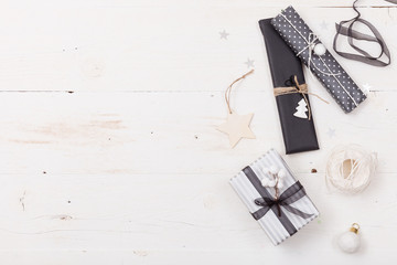 Top view on nice Christmas gifts packed in black and striped paper and decorated with stars on wooden background. Presents and decor elements. Holidays and winter concept.