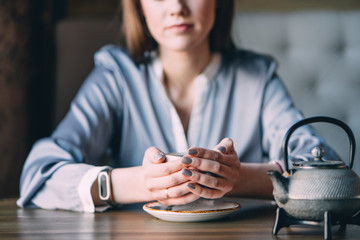 Young Woman Holding Cup of Tea Sitting in a Cafe, slective focus, close up