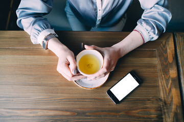 Young Woman Holding Cup of Tea Sitting in a Cafe, top view, copy space.