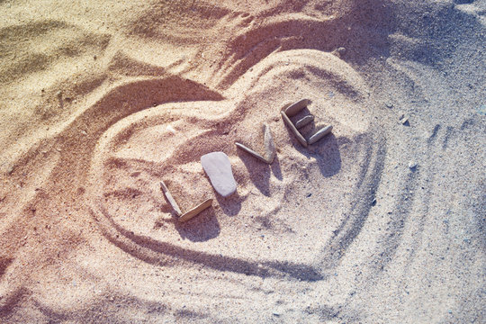 Word love made from stones and heart shape on a sandy beach