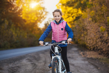 Obraz premium girl on a bicycle in the sunny autumn forest. girl cycling outdoors