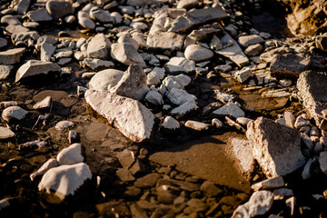 Stone beneath serene river water, river water waves brushing through the stones fresh water stream in mountain brook, close up