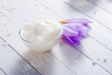 cosmetic cream and autumn crocus herbal flower on white wooden table