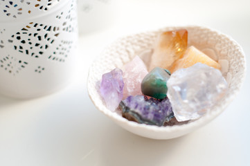 Fototapeta na wymiar Healing crystals on a white table including: Amethyst Point and Cluster, Agate, Aventurine, Clear Quartz, Citrine, Calcite and Rose quartz. Gemstones are full of healing energy and good vibes.