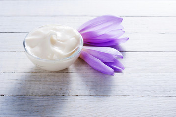 cosmetic cream and autumn crocus herbal flower on white wooden table