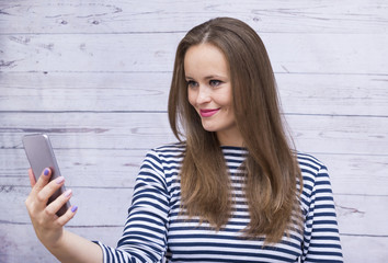 girl with long hair in vest looking at gadget, girl looking at phone
