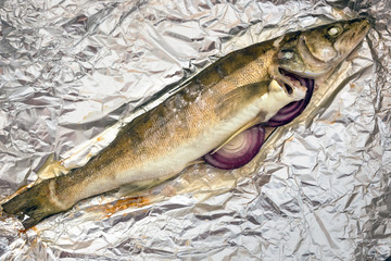 Pike perch fish baked in aluminum foil with red onions.
