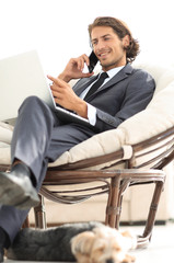 businessman talking on smartphone sitting in chair in his house