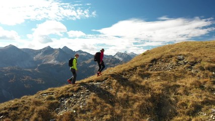 4K sport footage, aerial drone view active people couple hiking on mountain ridge on sunny day in autumn high above in middle of amazing mountains 
