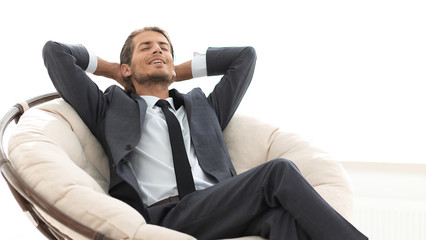 young businessman meditating in big comfortable armchair
