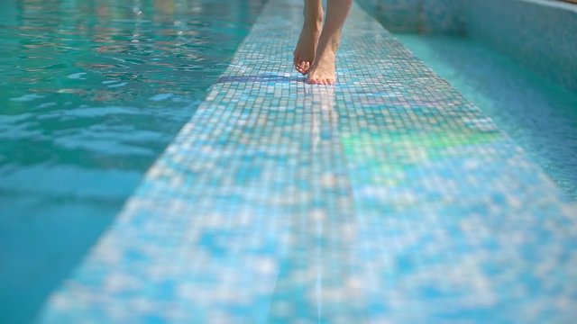 Beautiful young woman in summer. Bikini girl walking by the pool, close-up of her legs. Relaxing in tropical. The concept of resort, dreams,travel, vacation, spa, beauty, relaxation. slow-motion.