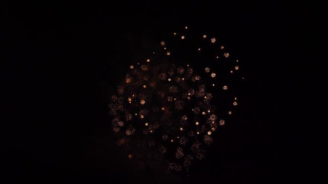 A mixture of several firework forms. Glittering olden balls, and sparkling balls, ending with red strobe firework.