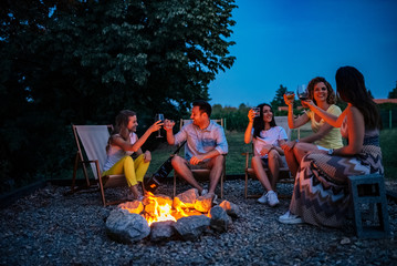 Friendship, happiness, summer vacation, holidays and people concept. Friends having a toast around...