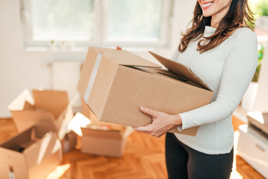 Moving in. Close-up image of female person carrying carton cardboard box.