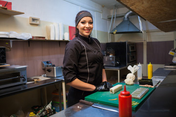Obraz premium woman chef prepares sushi on restaurant kitchen
