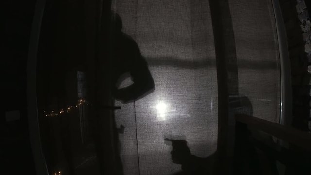 Shadows of two persons with gun and scrap. Dangerous criminals getting into apartment for commit crime. Darkness. Night.