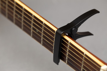 Black capo guitar on flat with gray paper background
