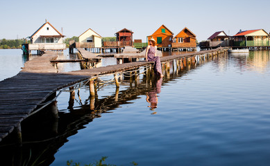 Fototapeta premium woman walking on the planks at floating village on lake Bokod, Hungary